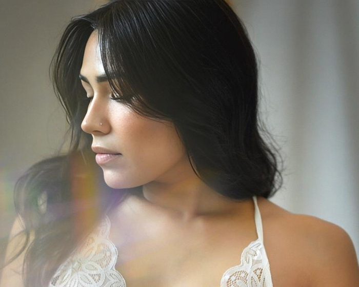 The same portrait shot through a handheld prism, with soft rainbow light across her hair and shoulder