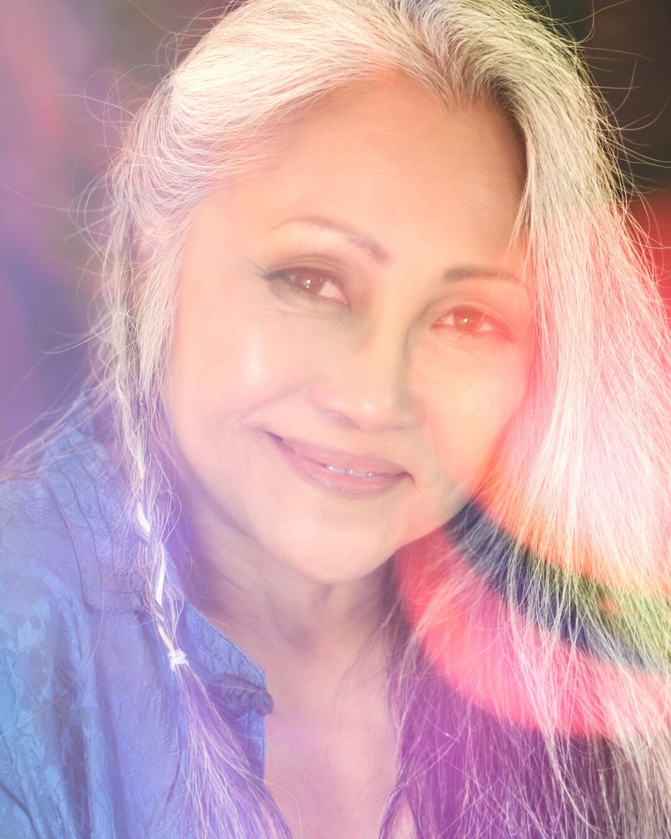 Prism photography portrait of a smiling woman with silver hair, a red and violet rainbow haze from a handheld prism across one side of her face